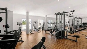 A gym with various exercise equipment, large windows, and a wooden floor.