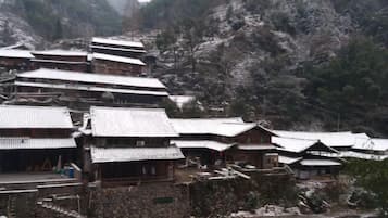 A traditional multi-story building with a steeply sloped roof, surrounded by rocky terrain and sparse vegetation.