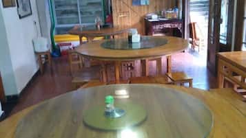 Un comedor con mesas y sillas redondas, un refrigerador y un ventanal.