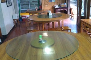 Un comedor con mesas y sillas redondas, un refrigerador y un ventanal.