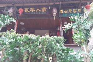 A traditional building with a wooden facade, signage indicating a restaurant, and a covered entrance. - Yongjia Yongping Home Inn (Yongjia)