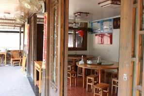 Un intérieur traditionnel en bois, avec des tables et des chaises, un ventilateur et une affiche accrochée au mur.