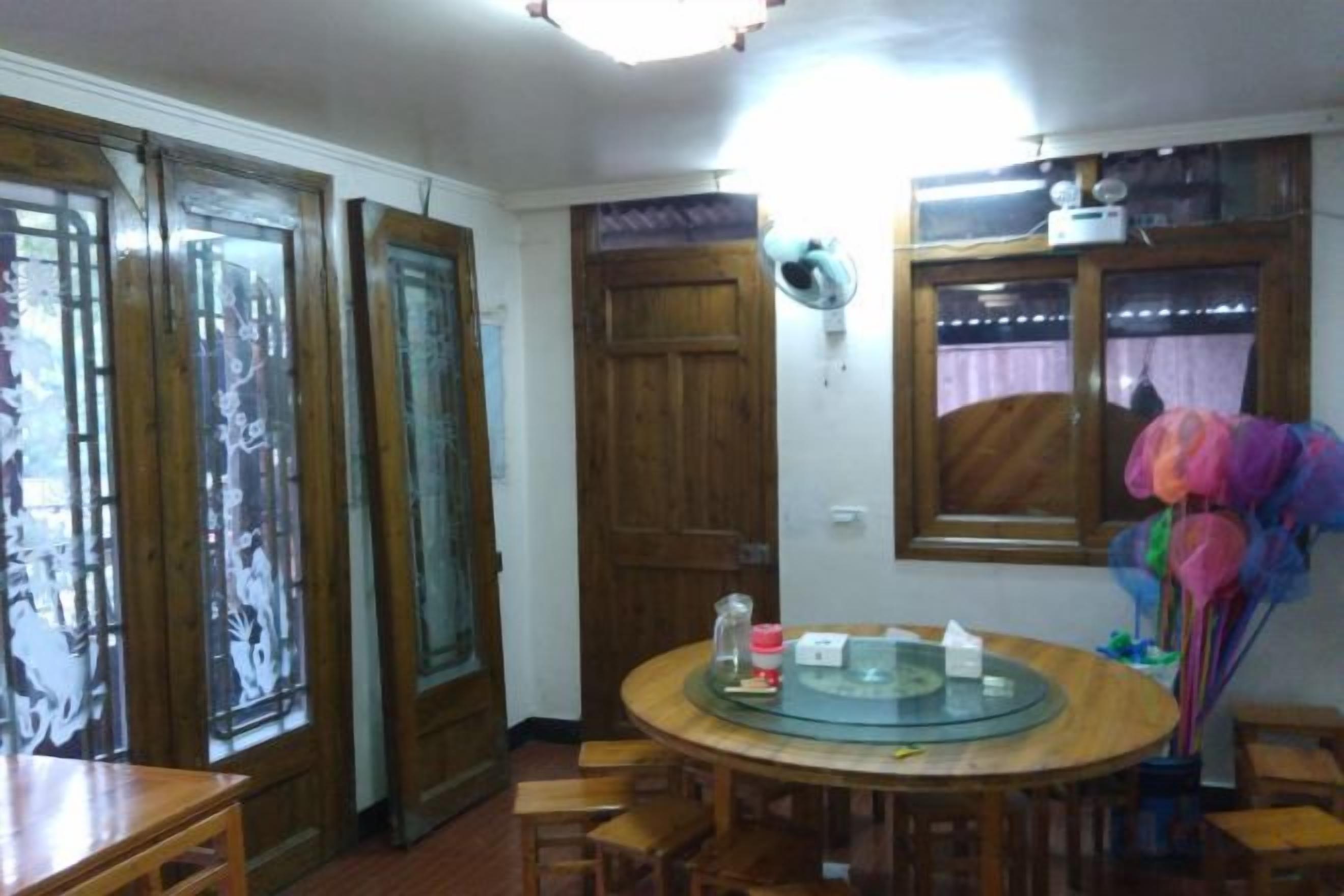 Un comedor con una mesa redonda, sillas, un ventilador y una ventana con cortinas.