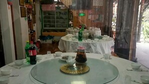 Zona de dinar amb taules rodones, tovallons blancs i diferents plats i ampolles.