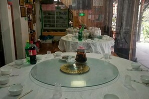 A dining area with round tables, white tablecloths, and various dishes and bottles. - Yongjia Yongping Home Inn (Yongjia)