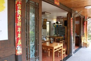 A wooden interior with a dining area, a staircase, and a traditional Chinese decorative banner. - Yongjia Yongping Home Inn (Yongjia)