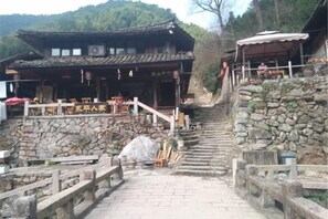 A traditional building with a stone staircase leading to a wooden deck. - Yongjia Yongping Home Inn (Yongjia)