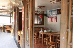 A traditional wooden interior with tables and chairs, a fan, and a poster on the wall. - Yongjia Yongping Home Inn (Yongjia)