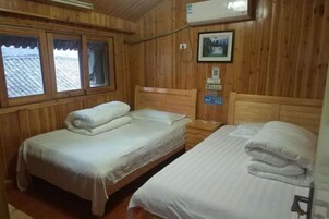 Habitación de cabaña de madera con dos camas, una ventana y aire acondicionado instalado en la pared.