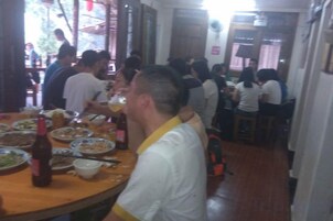 A dining area with tables set for multiple people, a variety of dishes, and a bottle of beer.