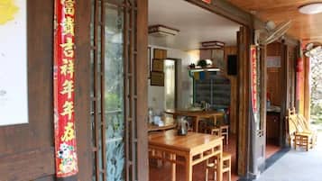 Un interior rústico de madera con comedor, cocina visible a través de un umbral abierto y techo de madera.