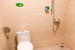 A small, tiled bathroom with a toilet, a shower, and a toilet paper holder. - Xing Qiang Hotel (Longmen)