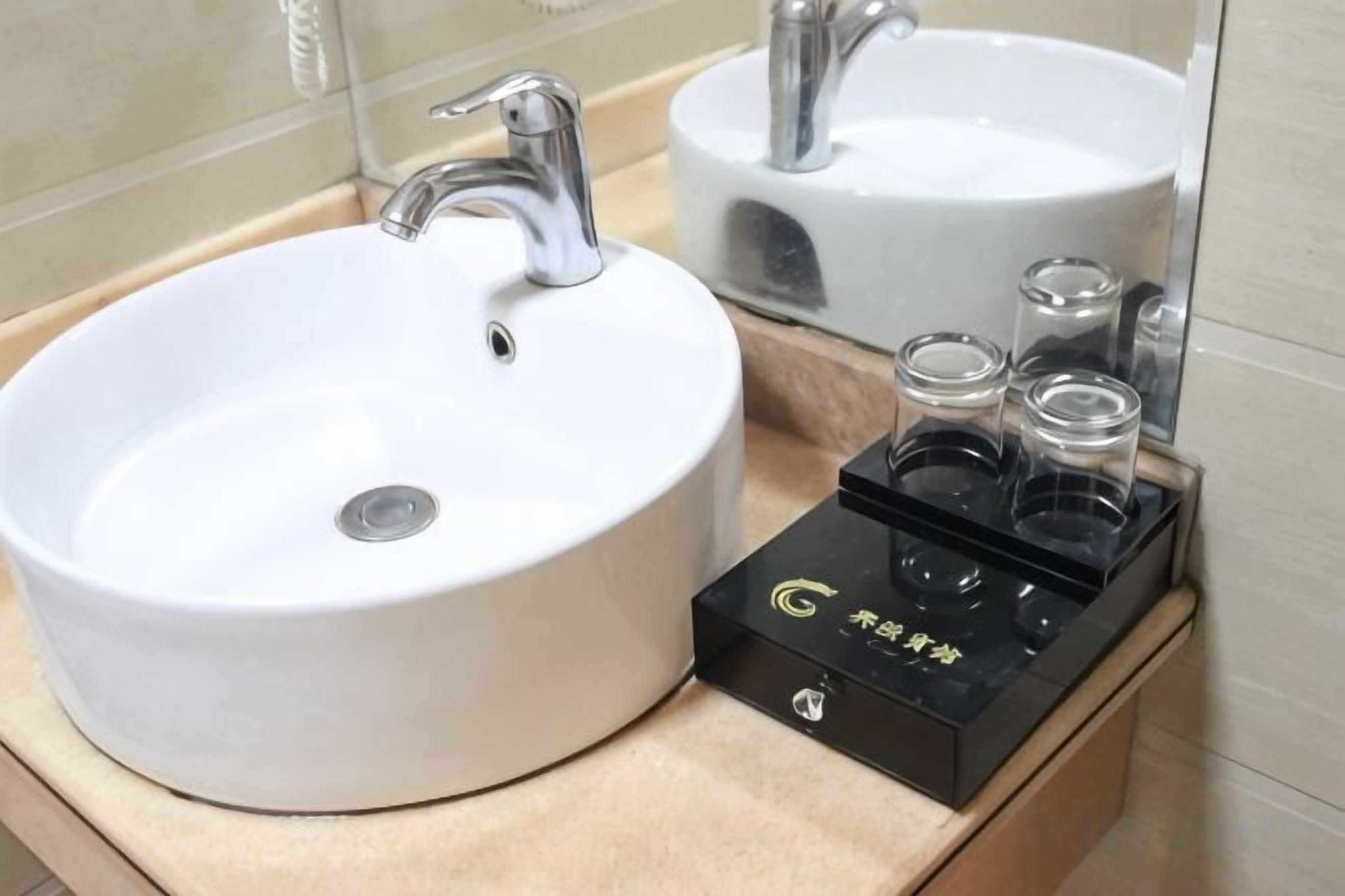 Un baño con un lavamanos blanco, un espejo y un dispensador de jabón negro.