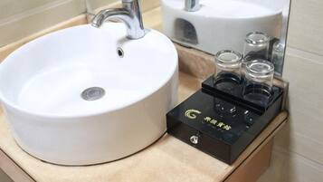 Un baño con un lavamanos blanco, un espejo y un dispensador de jabón negro.