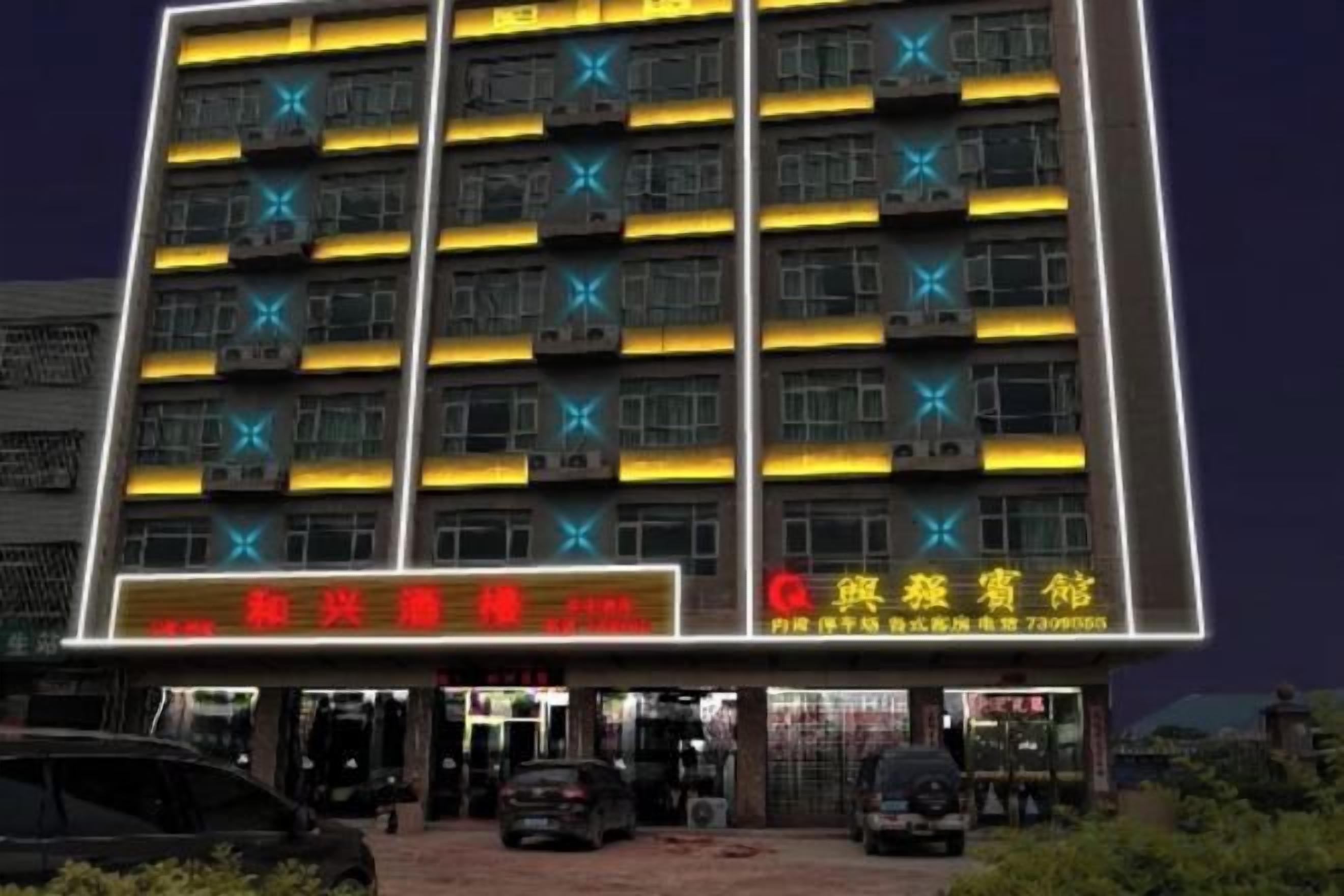 Un hotel de varios pisos con letreros iluminados y unidades de aire acondicionado.