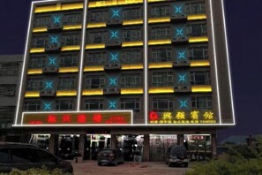 A multi-story hotel with illuminated signage and air conditioning units. - Xing Qiang Hotel (Longmen)