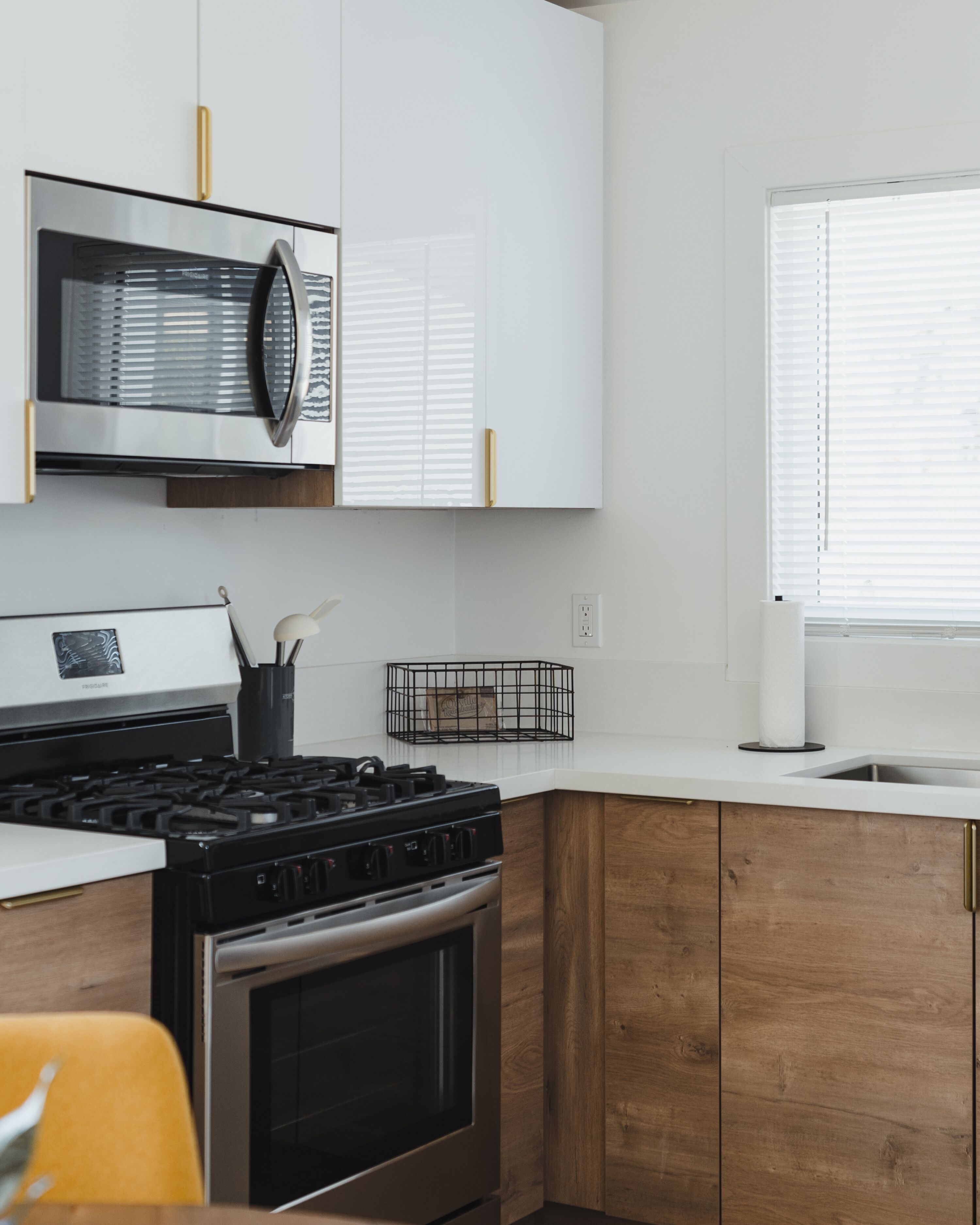 Una cucina moderna con mobili bianchi, piano cottura in acciaio inossidabile e forno a microonde.