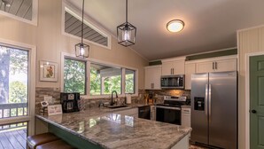 A kitchen with a large island, stainless steel appliances, and a view of the outdoors. - Fairway Gem at Spruce Pine - EV charge port, hot tub, fishing access (Spruce Pine)