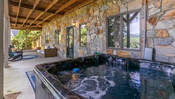 A stone-walled spa area with a hot tub and seating. - Fairway Gem at Spruce Pine - EV charge port, hot tub, fishing access (Spruce Pine)