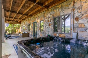 Zona de spa con paredes de piedra, una bañera de hidromasaje y asientos.
