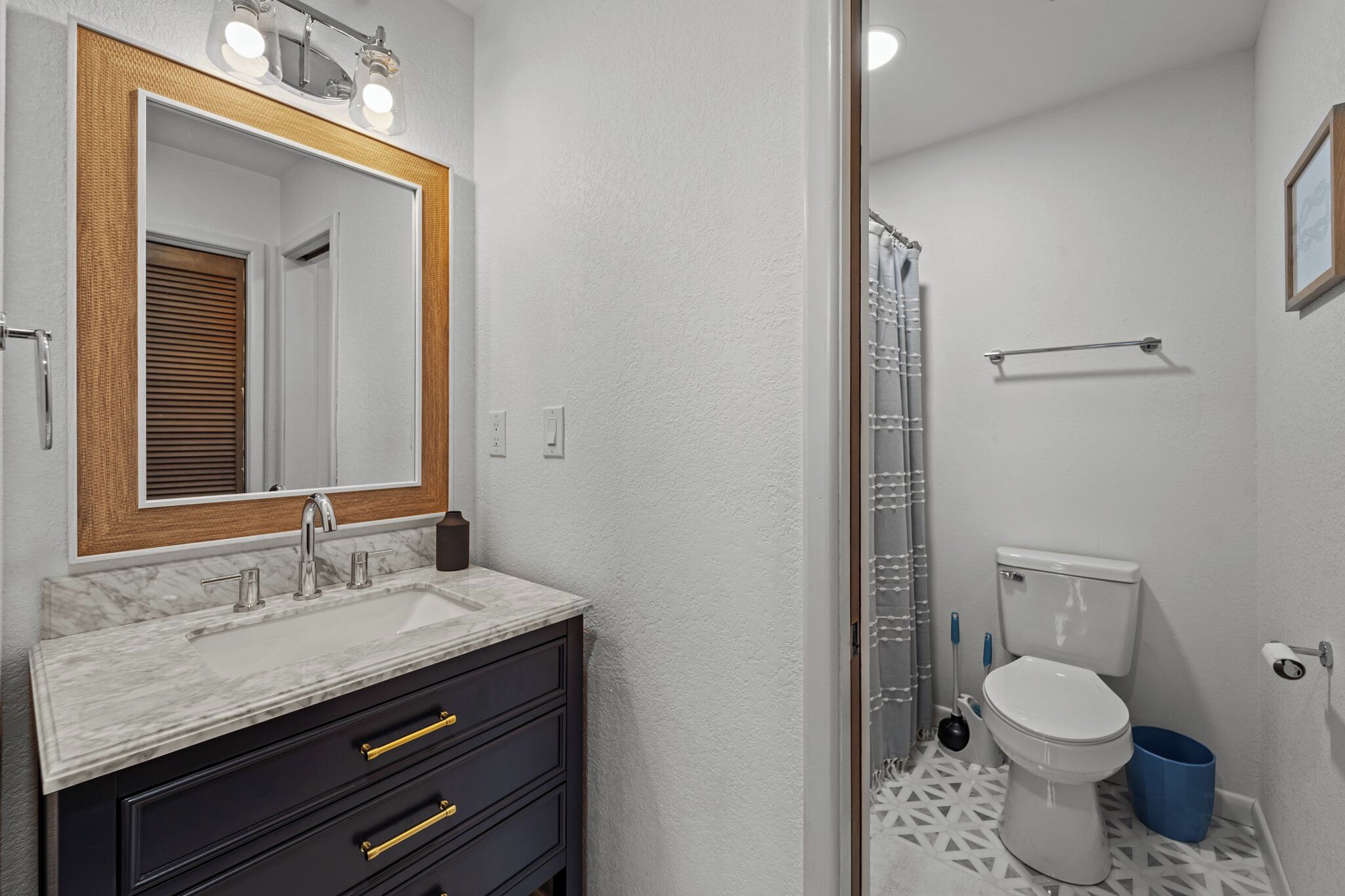 A bathroom with a white marble sink, dark vanity, and a white toilet.
