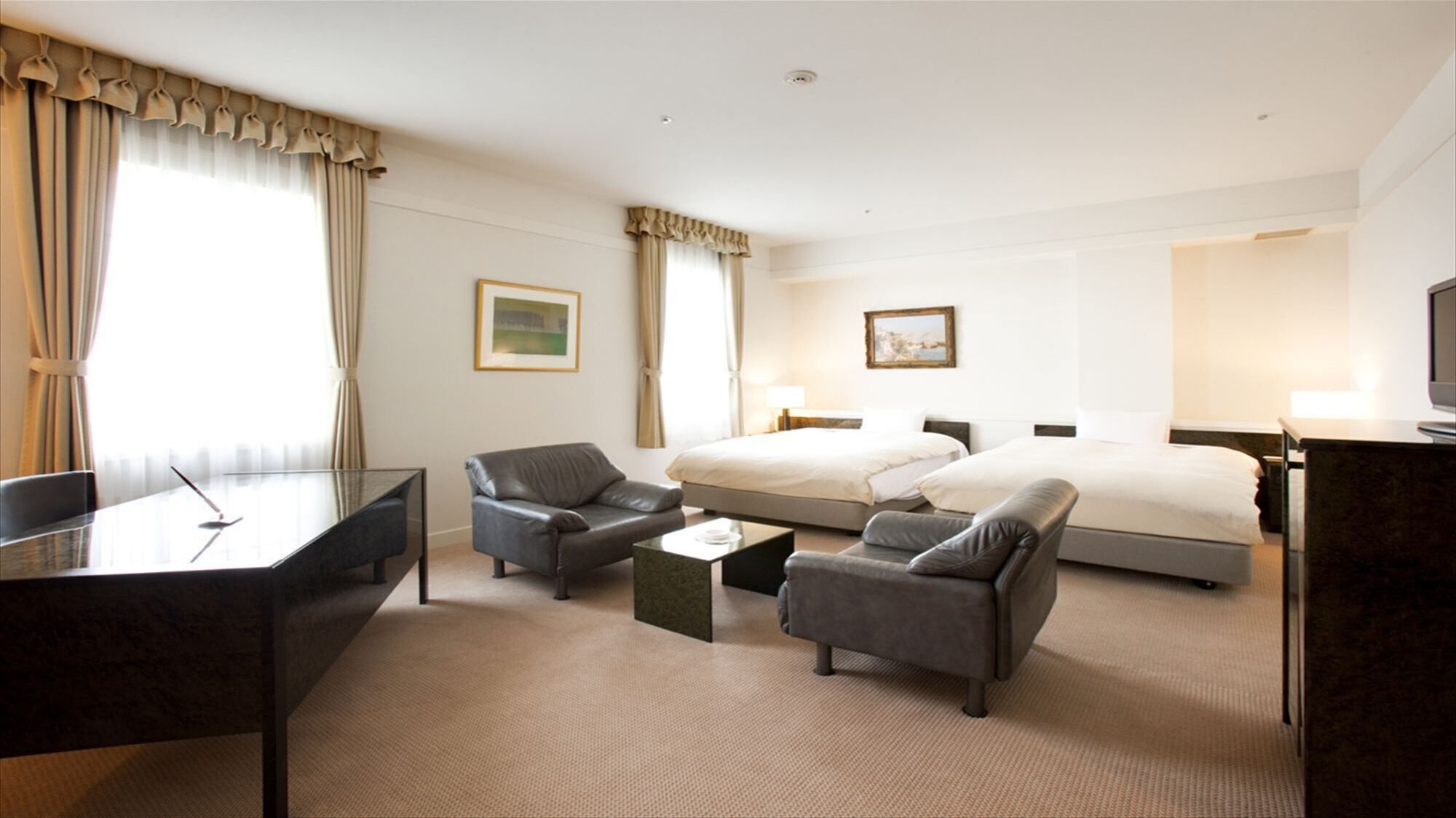 Ein Hotelzimmer mit einem Bett, zwei Sofas, einem Schreibtisch und einem Fernseher.
