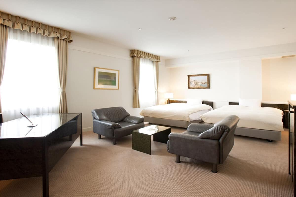 Ein Hotelzimmer mit einem Bett, zwei Sofas, einem Schreibtisch und einem Fernseher.