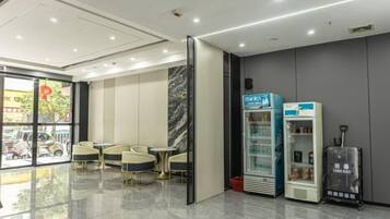 A modern interior with seating, vending machines, and a glass door leading outside.