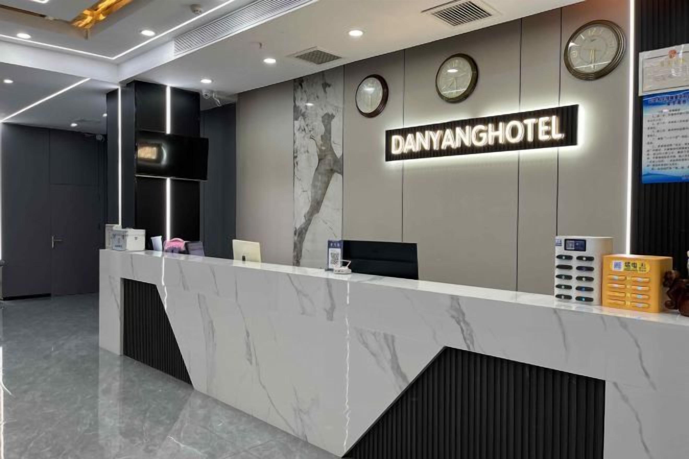 A reception desk with a marble top, clocks, and a sign reading "DANYANGHOTEL".