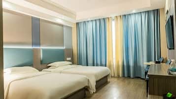 A hotel room with two beds, a desk, a TV, and curtains.