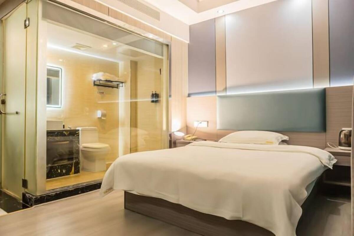 A modern hotel room with a glass-enclosed shower, a large bed, and a minimalist design.