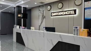 A hotel reception desk with a marble counter, a clock, and a sign that reads 'DANYANGHOTEL.'