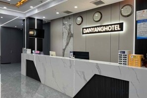 A hotel reception desk with a marble counter, a clock, and a sign that reads 'DANYANGHOTEL.' - Danyang Hotel (Guiyang)