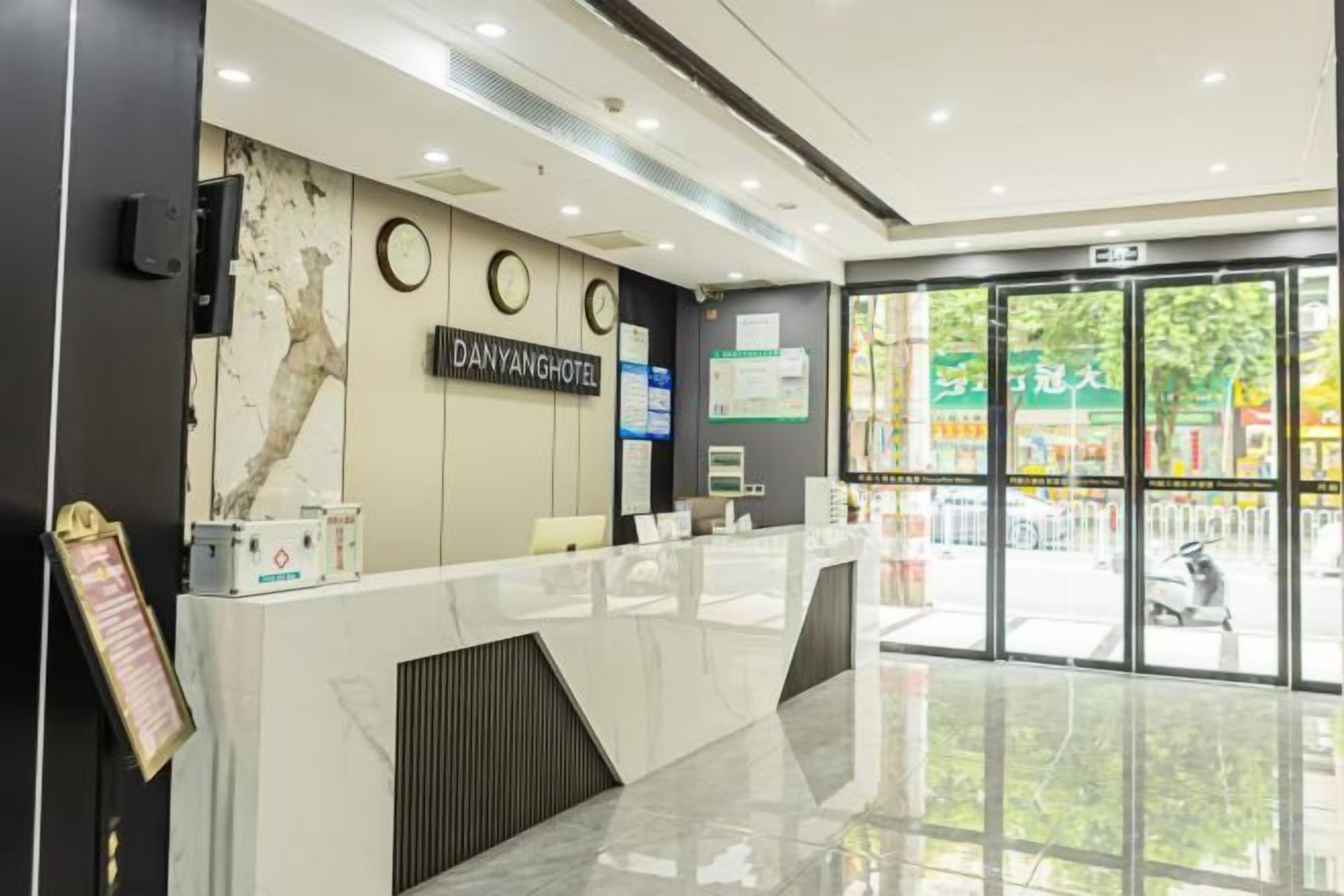 A hotel reception area with a marble counter, a reception desk, and a view of the street outside.