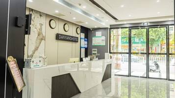 A hotel reception area with a marble counter, a reception desk, and a view of the street outside.