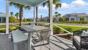 A covered patio with a table and chairs, overlooking a residential area with palm trees and houses. - Experience the irresistible charm of Cayo Coco Cottage! (Naples)