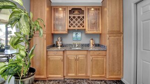 A kitchen with wooden cabinets, a granite countertop, and a potted plant. - Pet Friendly Canal Front 3-Bedroom Grand Villa with Pool, Linai and Dock (Port Charlotte)