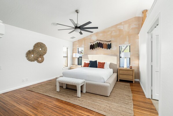 A modern bedroom with a large bed, a ceiling fan, and a wall-mounted light fixture. - Unique Chique backyard! Games, pool & so much more! (Scottsdale)