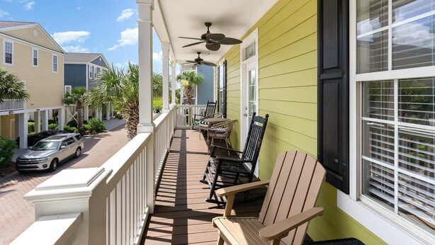 A covered porch with ceiling fans, outdoor seating, and a view of neighboring houses. - Angler Villas 3 (Murrells Inlet)