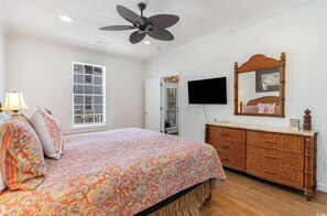 A bedroom with a bed, a dresser, a ceiling fan, a TV, and a window with blinds. - Angler Villas 3 (Murrells Inlet)