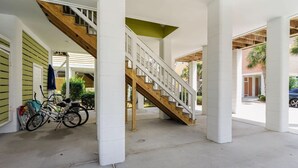 A covered outdoor area with a wooden staircase, concrete floor, and white pillars. - Angler Villas 3 (Murrells Inlet)
