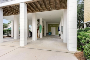 Un espace extérieur abrité, doté de piliers blancs, d’un plafond en bois et d’une enseigne verte.