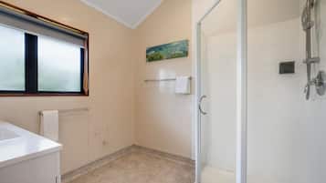 Un baño con cabina de ducha de vidrio, un lavamanos, un perchero para toallas y un cuadro en la pared.