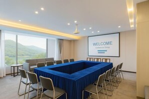 A conference room with a long table, chairs, a projector screen displaying 'WELCOME', and a view of the outdoors. - Yiju Haoting Hotel (Shangri-La)