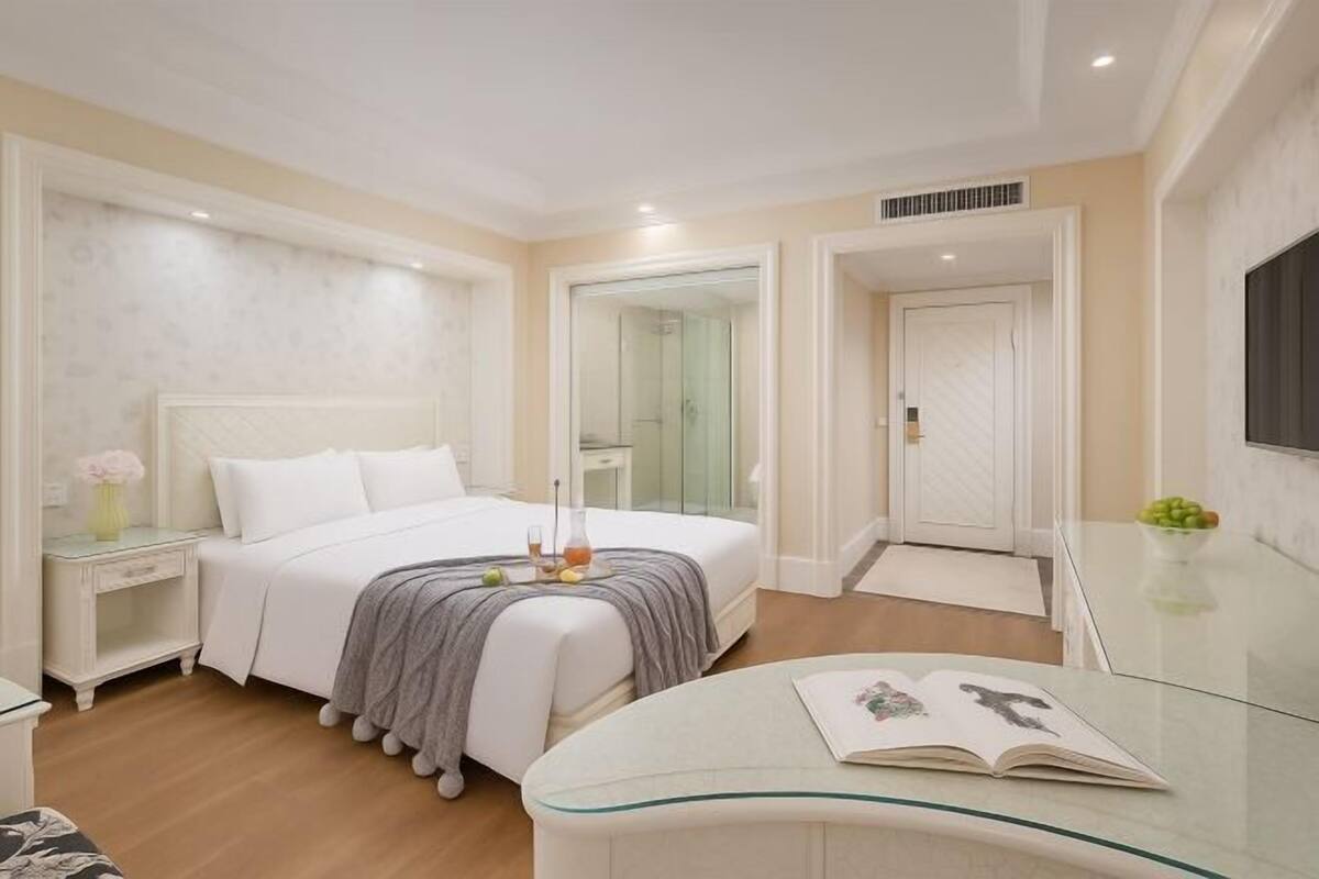 A modern bedroom with a bed, bedside table, and a glass table with a book.
