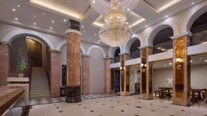 A spacious lobby with a grand chandelier, marble columns, and a checkered floor pattern. - Yiju Haoting Hotel (Shangri-La)