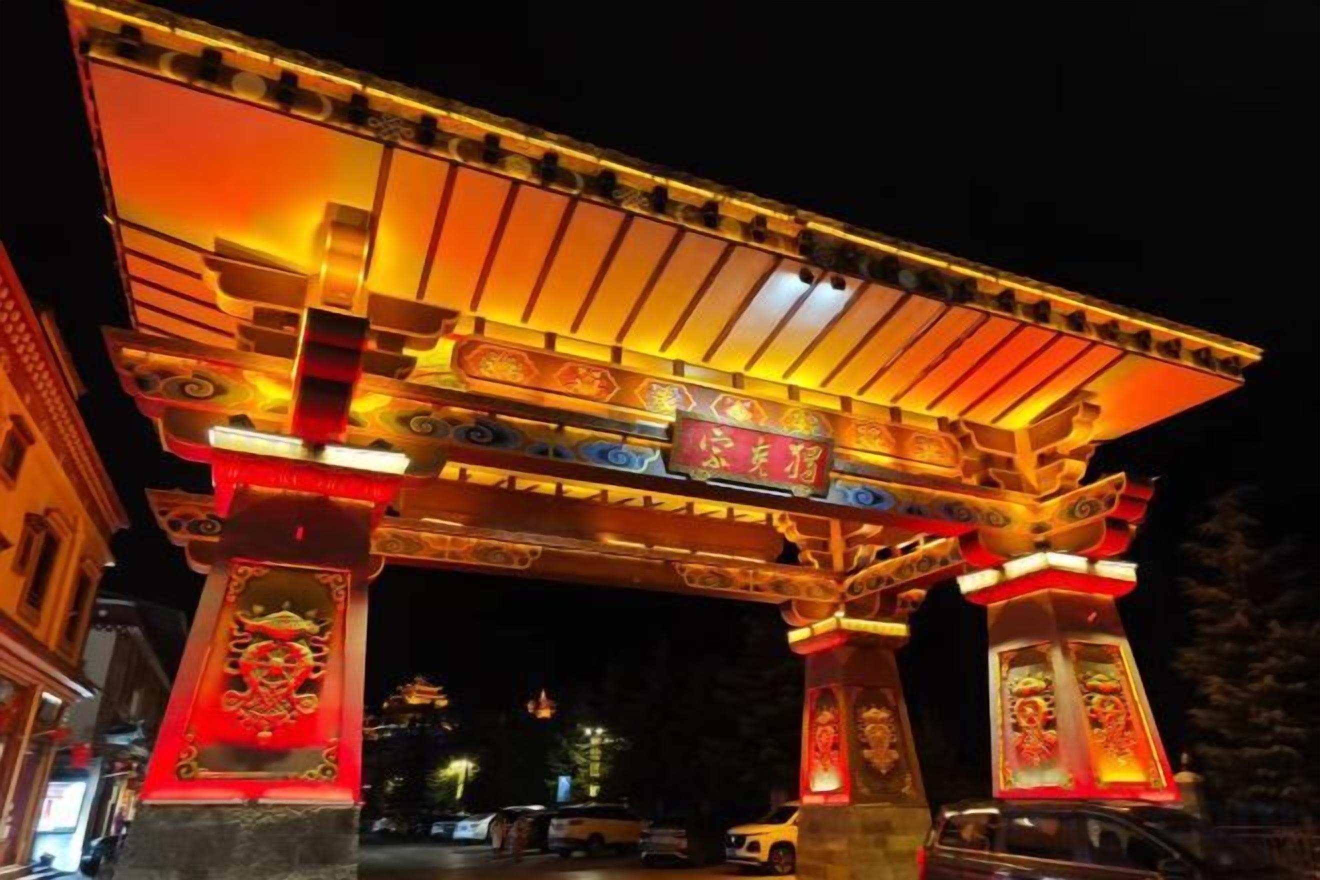 A traditional Japanese torii gate at night with illuminated pillars and a roof.