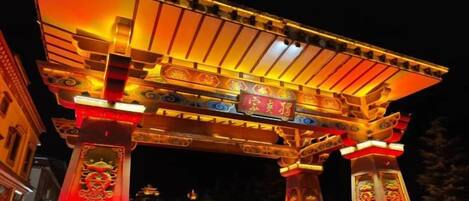 A traditional Japanese torii gate at night with illuminated pillars and a roof.