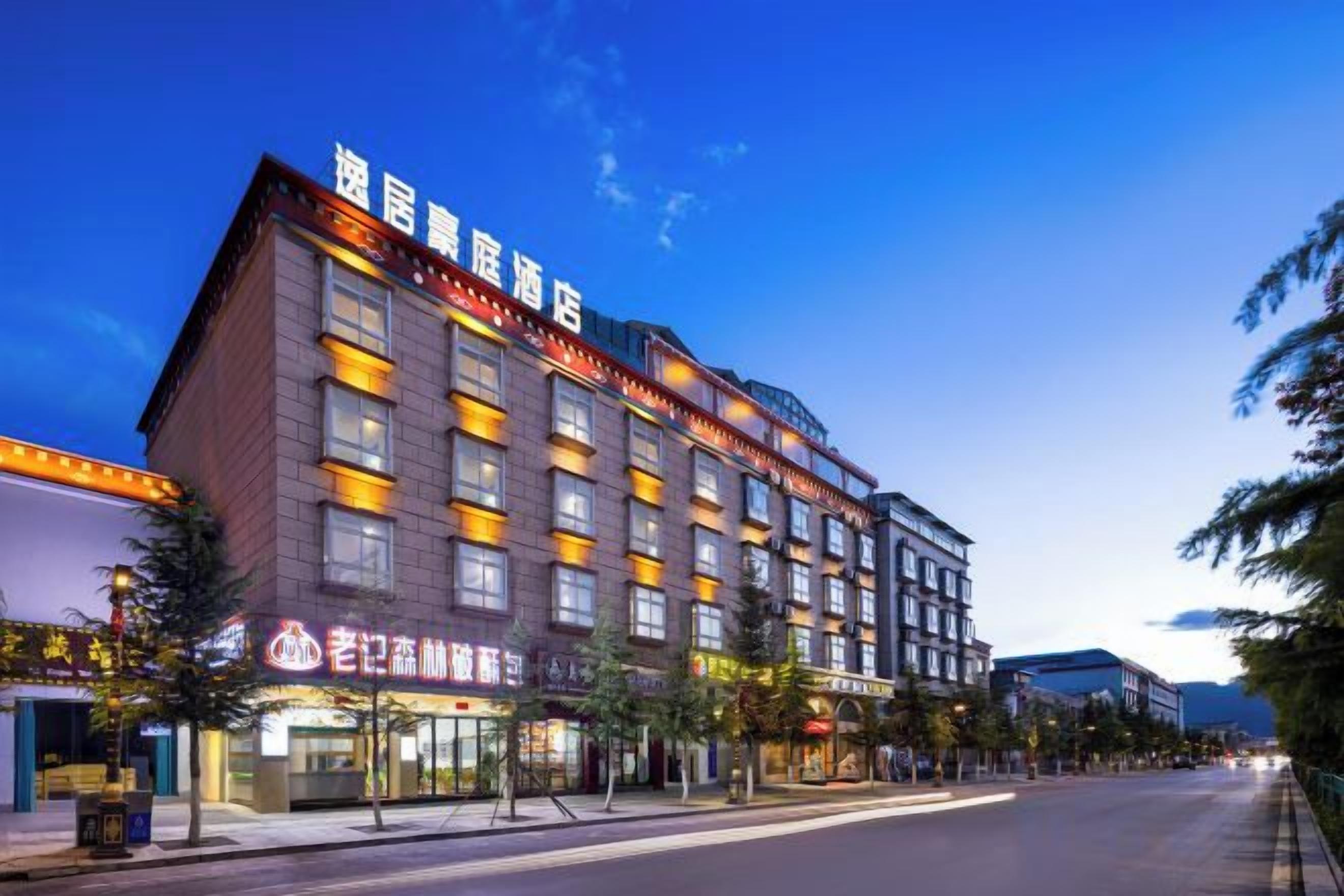 A multi-story hotel with a prominent sign at the top, a row of windows on the facade, and a street in front.