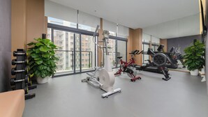 A modern gym with cardio machines, dumbbells, and potted plants.